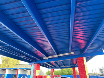 Blue metal roof structure with red accents, see our work.