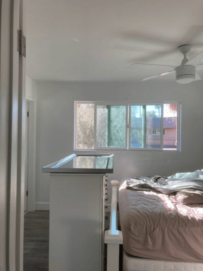 Bright and airy bedroom with white walls, large windows, and modern ceiling fan