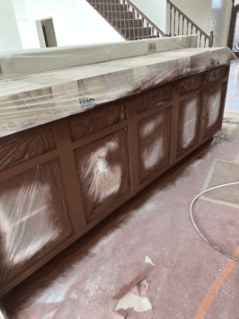 Brown painted kitchen cabinets covered in plastic sheeting, showcasing our work.
