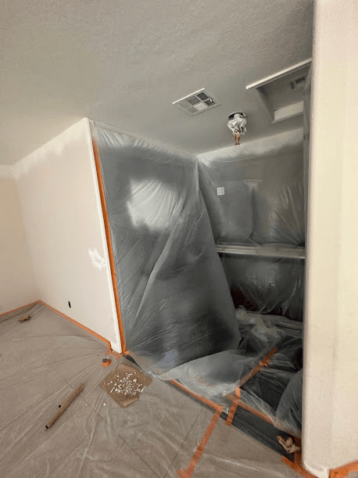 Room with plastic coverings and masking tape, ready for painting