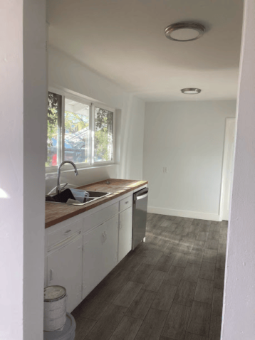 Bright kitchen with white cabinets, wood countertops, and modern flooring.