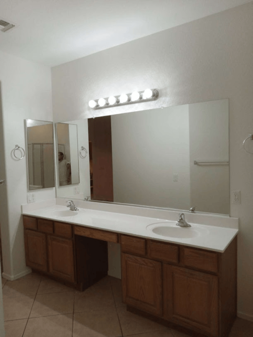 Bathroom with double sinks, large mirror, and wooden cabinets.