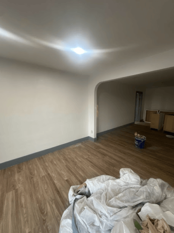 Room with wooden floor and arched doorway, recently painted