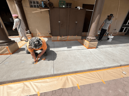 Workers prepping and masking the sidewalk for painting