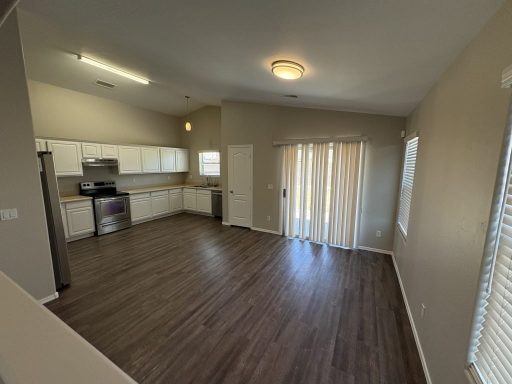 A modern furnished open-concept kitchen and living area with white cabinets