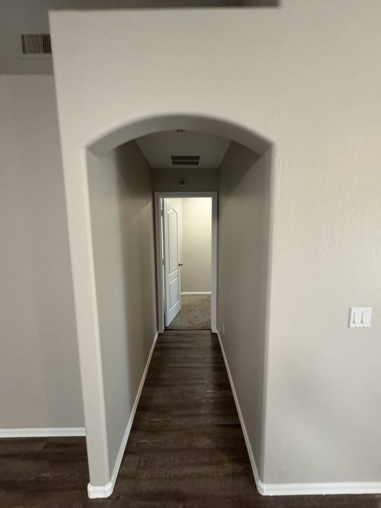 Hallway with grey walls leading to a room