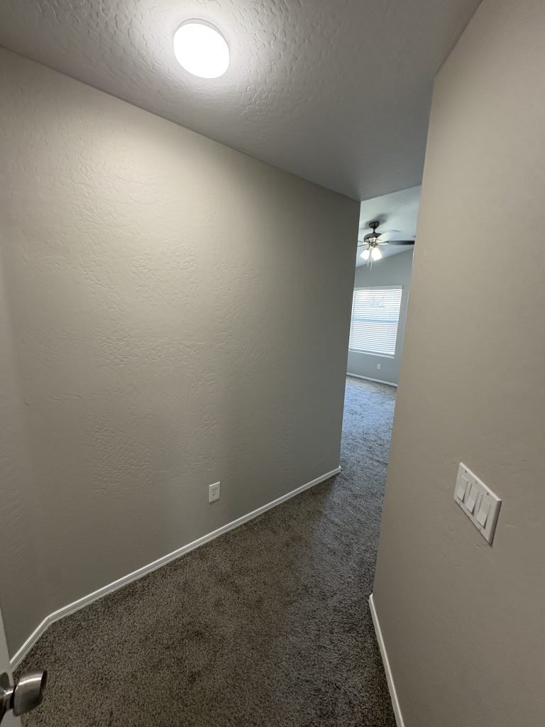 Hallway with grey walls, carpeted floor, and a doorway