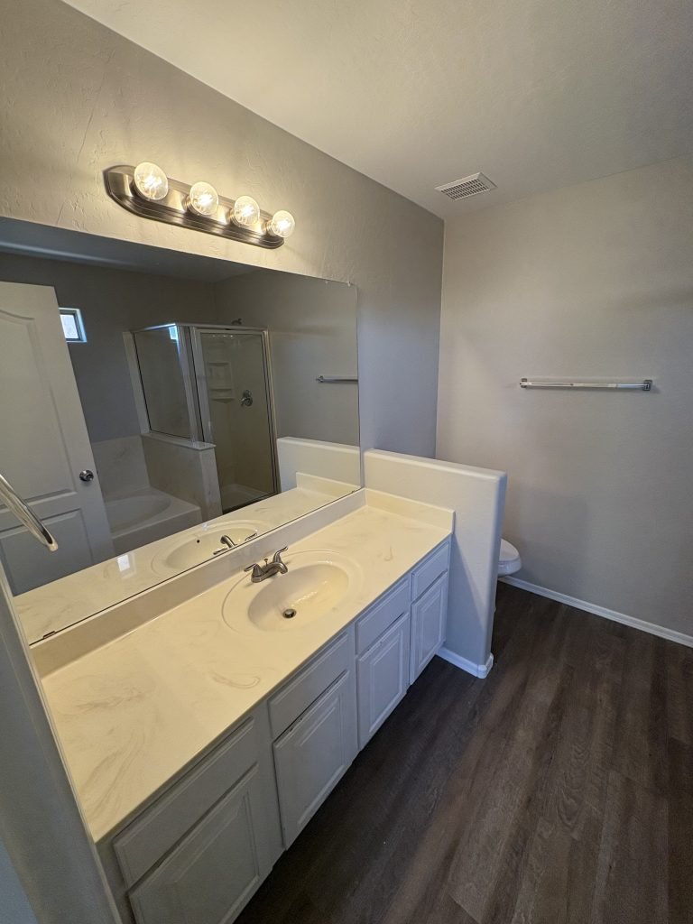 Empty bathroom with white cabinets and a mirror