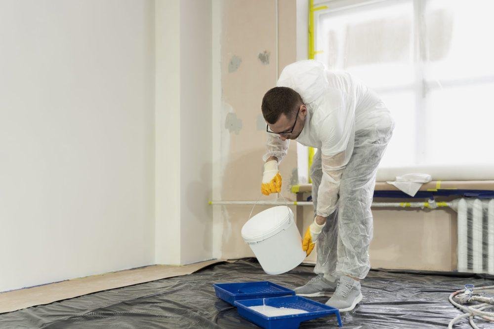 Painter in protective gear pouring paint for interior painting in Surprise, AZ.