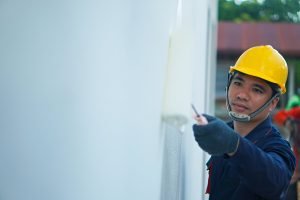 Asian painter is painting white house wall, house decoration and construction idea