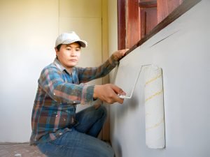 Workers painter are painting the wooden walls of the room