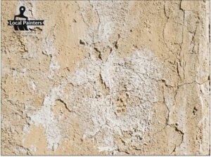 A close-up of a stucco wall showing signs of sun fading and chalking in a desert environment.