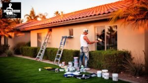Professional painter applying exterior paint to a house with ladders and supplies.